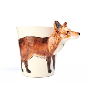 May include: A ceramic mug featuring a 3D fox design. The fox is painted in shades of brown and white, with a realistic appearance. The mug is a great gift for animal lovers.