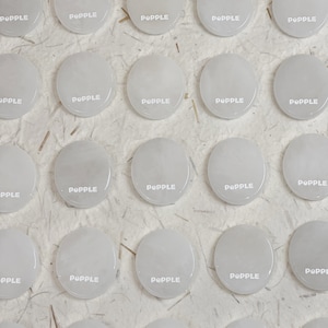 May include: A collection of 20 white round coasters with the word "POPPLE" printed in white on each coaster.