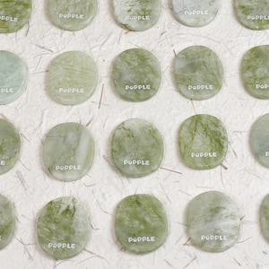 Pode incluir: Uma coleção de 18 pedras redondas de jade verde com a palavra "POPPLE" impressa em cada uma.