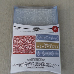 May include: A set of four embossing folders for creating textured designs. The folders feature holiday-themed patterns, including a damask design, a banner with the text "Happy Everything", a banner with the text "Season's Greetings", and a geometric pattern. The folders are packaged in a clear plastic sleeve with a white label that includes the product name, product number, and instructions for use.