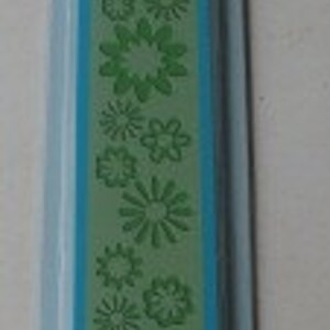 May include: A blue and green plastic craft die with a floral design. The die is packaged in a clear plastic sleeve with the word "Cuttlebug" printed on it.