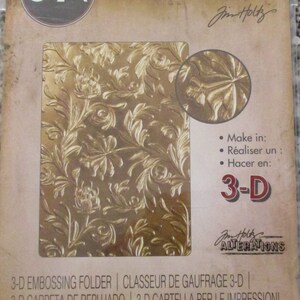 May include: A gold 3-D embossing folder with a floral design. The folder is labeled "3-D Texture Fades" and "Jim Holtz Alterations".