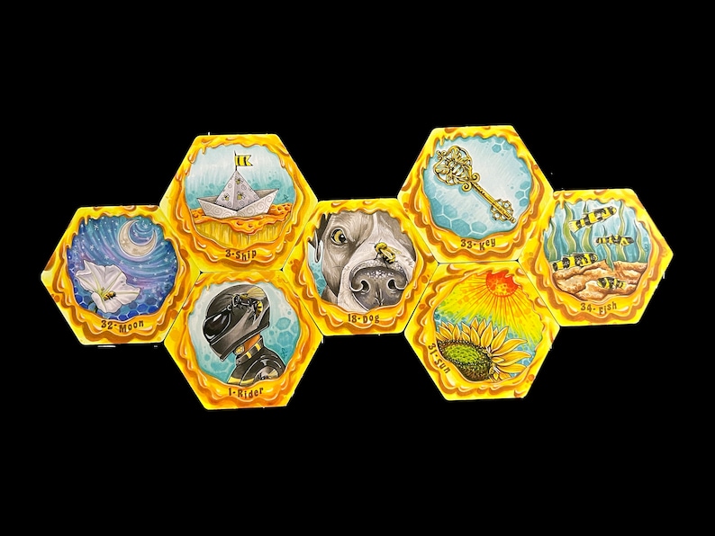May include: A set of hexagonal game tiles with various illustrations, including a ship, a key, a dog, a rider, a moon, a sun, and a fish. Each tile has a number and a word describing the image.