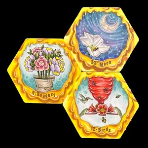 May include: Three hexagonal honey-themed tiles with illustrations of a bouquet of flowers, a hummingbird feeder with hummingbirds, and a moon and a flower. The tiles are labeled "9-Bouquet", "12-Birds", and "32-Moon".