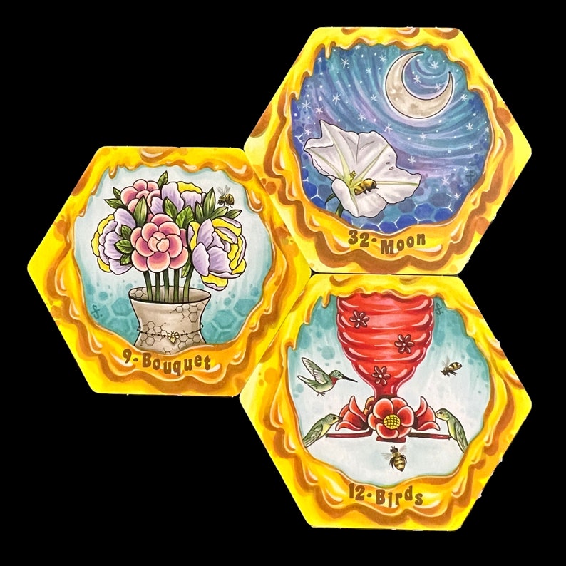 May include: Three hexagonal honey-themed tiles with illustrations of a bouquet of flowers, a hummingbird feeder with hummingbirds, and a moon and a flower. The tiles are labeled "9-Bouquet", "12-Birds", and "32-Moon".