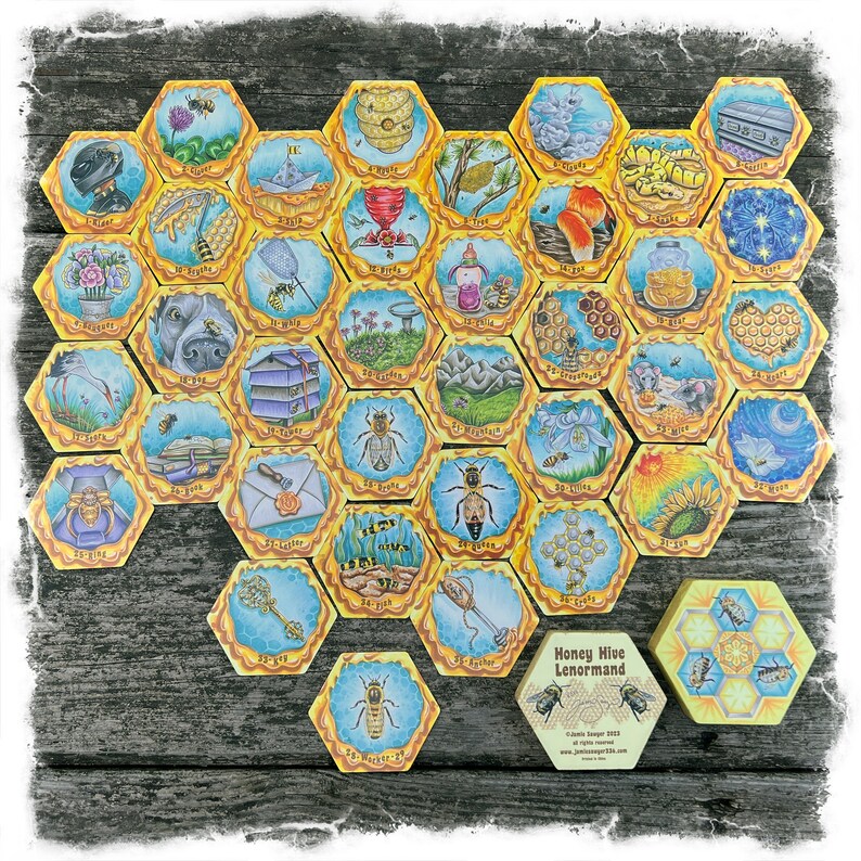 May include: A Honey Hive Lenormand deck of cards with 36 hexagonal cards featuring illustrations of bees, honeycombs, flowers, and other nature-themed imagery. The cards are laid out in a honeycomb pattern on a wooden surface. The box for the deck is also visible in the image.