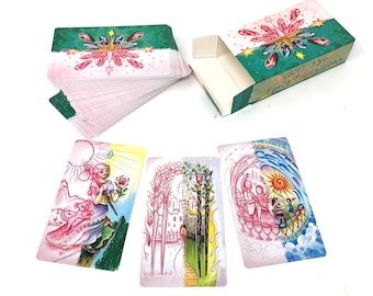 May include: A deck of Tarot cards with a matching box. The box and card backs have a green and pink design with crystals and stars. Three cards are displayed, each with colorful illustrations of figures and scenes.