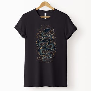 una t-shirt nera con la silhouette di un serpente formata da stelle, lune e soli
