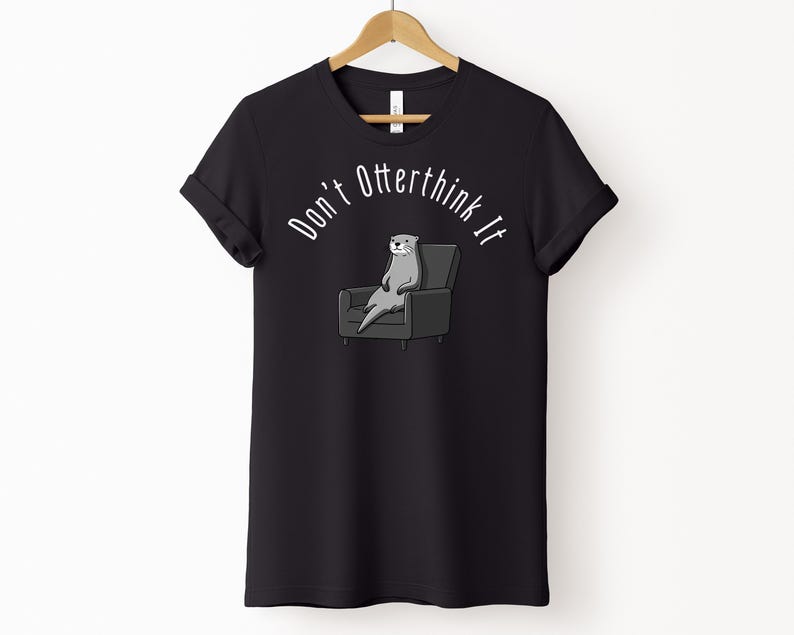 una tshirt nera con una lontra su una poltrona e sopra di lei la scritta "Don't otterthink it"