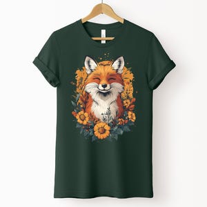 una maglia color verde foresta con l'immagine di una volpe sorridente circondata da fiori in stile cottagecore