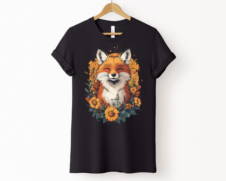 una maglia nera con l'immagine di una volpe sorridente circondata da fiori in stile cottagecore