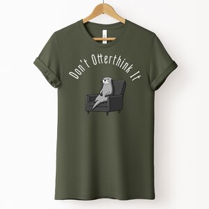 una tshirt color verde militare con una lontra su una poltrona e sopra di lei la scritta "Don't otterthink it"