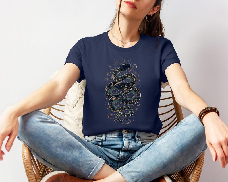 una donna con una t-shirt color marina militare con la silhouette di un serpente formata da stelle, lune e soli