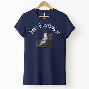 una tshirt color marina militare con una lontra su una poltrona e sopra di lei la scritta "Don't otterthink it"