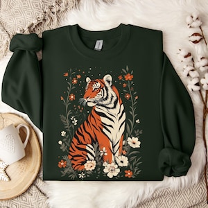 May include: A dark green sweatshirt with a graphic print of a tiger surrounded by flowers. The tiger is orange and black with white stripes. The flowers are in shades of pink, orange, and yellow.