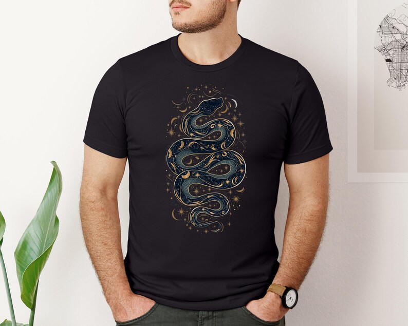 un uomo con una t-shirt nera con la silhouette di un serpente formata da stelle, lune e soli