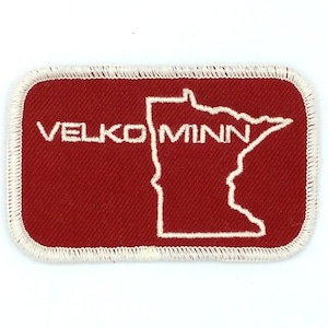 May include: Red rectangular patch with white stitching around the edges. The patch features a white outline of the state of Minnesota and the text "VELKO MINN" in white.