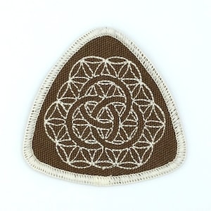 May include: A brown triangular patch with a white embroidered geometric design. The design is a flower of life pattern.
