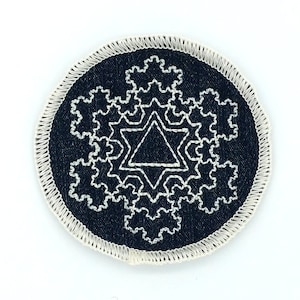 May include: A black and white embroidered patch with a geometric design. The design features a star with a triangle inside. The patch is circular and has a white border.