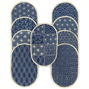 May include: Set of nine blue oval pot holders with white embroidered geometric patterns.