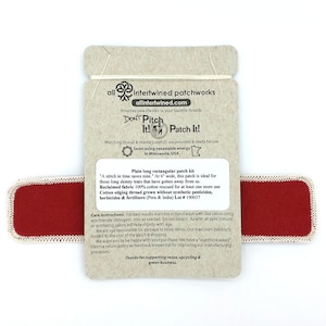 May include: Red rectangular fabric patch with white edging. The patch is 15 cm wide and is ideal for mending tears in fabric. The back of the patch has instructions for care and information about the fabric's origin. The text on the back reads "Don't Pitch It! Patch It!" and "Plain long rectangular patch kit".
