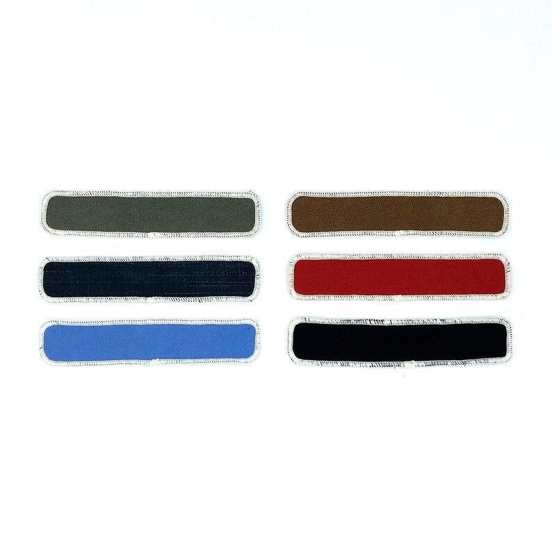 May include: Six fabric patches in different colours. The patches are rectangular and have a white border. The colours are green, brown, red, blue, and black.