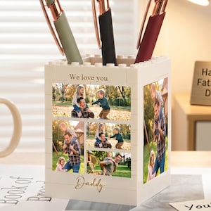 May include: A personalized pen holder with family photos and the words "We love you" and "Daddy". Three pens with rose gold accents are in the holder. A mug that says "Best Dad Ever" and a "Happy Father's Day" sign are also visible.