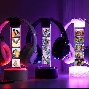 Pu&ograve; includere: Tre supporti per cuffie illuminati con display fotografici personalizzati. Le cuffie sono bianche e nere, con una luce rosa, blu e bianca. Ogni supporto ha un display fotografico rettangolare con pi&ugrave; immagini. Un telecomando &egrave; davanti.