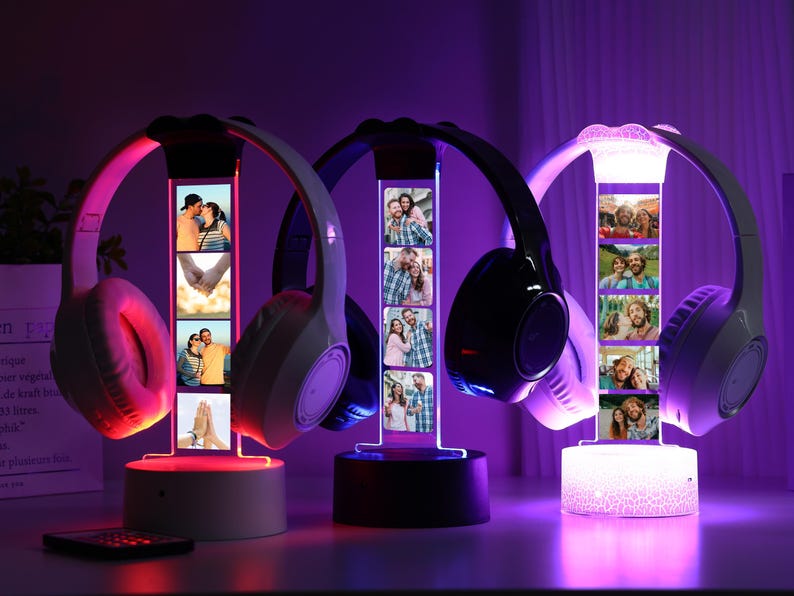 Pu&ograve; includere: Tre supporti per cuffie illuminati con display fotografici personalizzati. Le cuffie sono bianche e nere, con una luce rosa, blu e bianca. Ogni supporto ha un display fotografico rettangolare con pi&ugrave; immagini. Un telecomando &egrave; davanti.