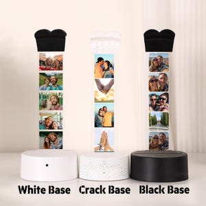 Pu&ograve; includere: Tre lampade espositive fotografiche con basi bianche, screpolate e nere. Ogni lampada presenta una serie di piccole foto e una parte superiore a forma di cuore. Le basi sono rotonde con un piccolo pulsante. Il testo "White Base", "Crack Base" e "Black Base" &egrave; in basso.