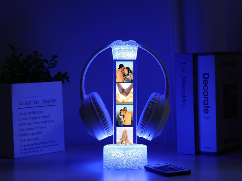Pu&ograve; includere: Una lampada a LED blu a forma di cuffia. La lampada presenta un display verticale con quattro piccole cornici per foto. La base e la parte superiore della lampada hanno un motivo strutturato e screpolato. Un telecomando &egrave; davanti alla lampada.