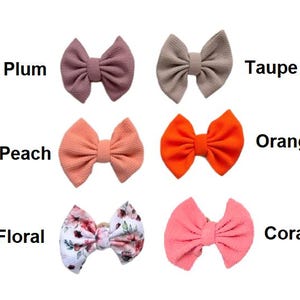 May include: Six fabric hair bows arranged in two columns. The left column features plum, peach, and floral patterned bows. The right column features taupe, orange, and coral bows. Each bow is labeled with its corresponding color name in black text.