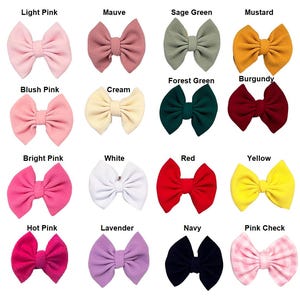 May include: A collection of sixteen fabric hair bows in various colors including light pink, mauve, sage green, mustard, blush pink, cream, forest green, burgundy, bright pink, white, red, yellow, hot pink, lavender, navy, and a pink checkered pattern.