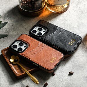 May include: Two phone cases with a leather texture. One is black with the initials "D.G." and the other is brown with the initials "K.H."