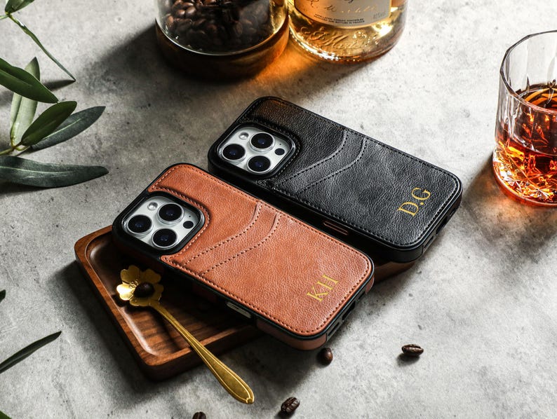 May include: Two phone cases with a leather texture. One is black with the initials "D.G." and the other is brown with the initials "K.H."