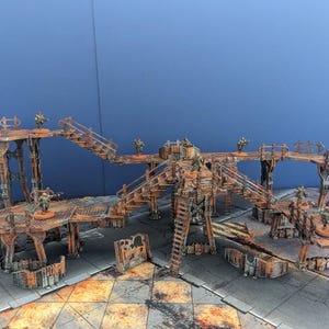 Op de afbeelding: Een gedetailleerde miniatuurterreinset met een roestige, industriële esthetiek. De set bevat verhoogde platforms, loopbruggen, trappen en ondersteunende structuren, allemaal geschilderd in bruin- en oranje tinten. Miniatuurfiguren zijn op de platforms geplaatst.
