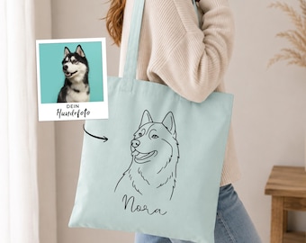 May include: A light blue tote bag featuring a black line art illustration of a husky dog's head and the name Nora written in cursive script below the drawing. A small square insert shows a photograph of the same husky dog with the text DEIN Hundefoto.