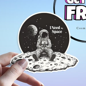 Puede incluir: Ilustración en blanco y negro de un astronauta sentado en la luna con estrellas en el fondo. El texto "I Need My Space" está escrito sobre el astronauta.