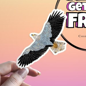 May include: A sticker featuring a detailed illustration of an eagle in flight. The eagle has black and white wings, a light blue body, and a yellow beak. The sticker is held by a hand against a gradient background with text that reads "Get Free".