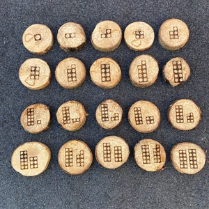 May include: Twenty wooden circles with different arrangements of small squares, resembling building blocks, burned into the surface.