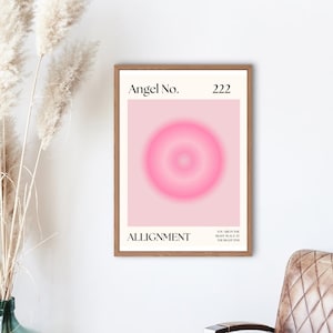 May include: A framed poster with a pink background and a pink circle in the center. The poster has the text "Angel No. 222" at the top and "ALIGNMENT" at the bottom. The text "NOW ARE IN THE RIGHT PLACE AT THE RIGHT TIME" is also on the poster.