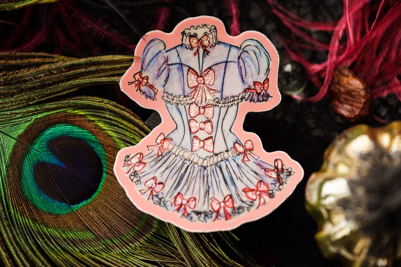 K&ouml;nnte beinhalten: Ein Aufkleber mit einer Aquarellillustration eines hellblauen Kleides mit rosa Schleifen. Das Kleid hat ein korsettartiges Oberteil und einen ger&uuml;schten Rock. Rote Schleifen zieren die &Auml;rmel, das Oberteil und den Rock. Der Aufkleber ist rosa umrandet.