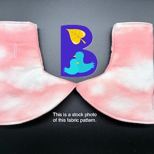 May include: A pair of pink and white tie-dye fabric boot covers with a vertical slit on each side. Between the covers is a purple logo featuring a yellow leaf and two blue birds, with the text: This is a stock photo of this fabric pattern.
