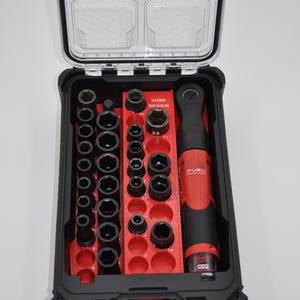 Puede incluir: Un juego de herramientas negro y rojo con tapa transparente. El juego incluye una variedad de enchufes y una llave de carraca roja y negra. La caja está etiquetada como "VORK DESIGN" y "FUEL".