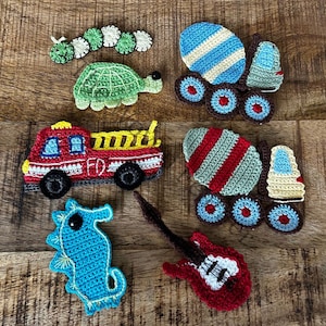 May include: A set of nine crocheted felt toys, including a red fire truck, a blue and white cement mixer, a green turtle, a blue seahorse, a red guitar, a green and red cement mixer, and a green caterpillar.