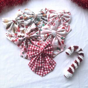 May include: Several fabric bows with festive Christmas patterns, such as candy canes and gingerbread men. One bow has a red and white gingham design. A decorative candy cane is also visible.
