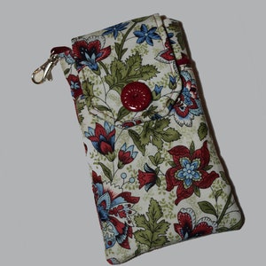 Peut inclure: Étui à lunettes à imprimé floral avec fermeture à bouton rouge et fermoir argenté. Le tissu présente des fleurs rouges, bleues et vertes sur fond crème. L'étui mesure environ 18 cm de long.