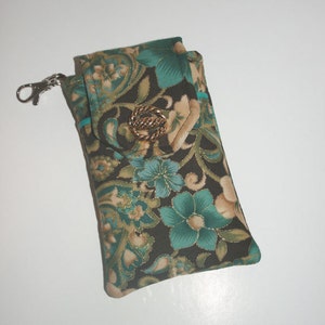 Peut inclure: Un étui de téléphone à motifs avec un fermoir doré et un bouton décoratif. L'étui présente un motif floral turquoise, beige et doré sur un fond sombre. Un clip argenté est attaché sur le côté.