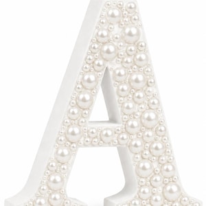 A freestanding capital letter in white, featuring a smooth matte finish on the sides and a front surface densely covered in white faux pearls of varying sizes, creating a textured, dimensional appearance across the entire letter.