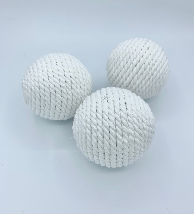 Puede incluir: Tres bolas de cuerda blancas, cada una hecha de cuerda blanca tejida apretadamente, est&aacute;n dispuestas sobre una superficie blanca.
